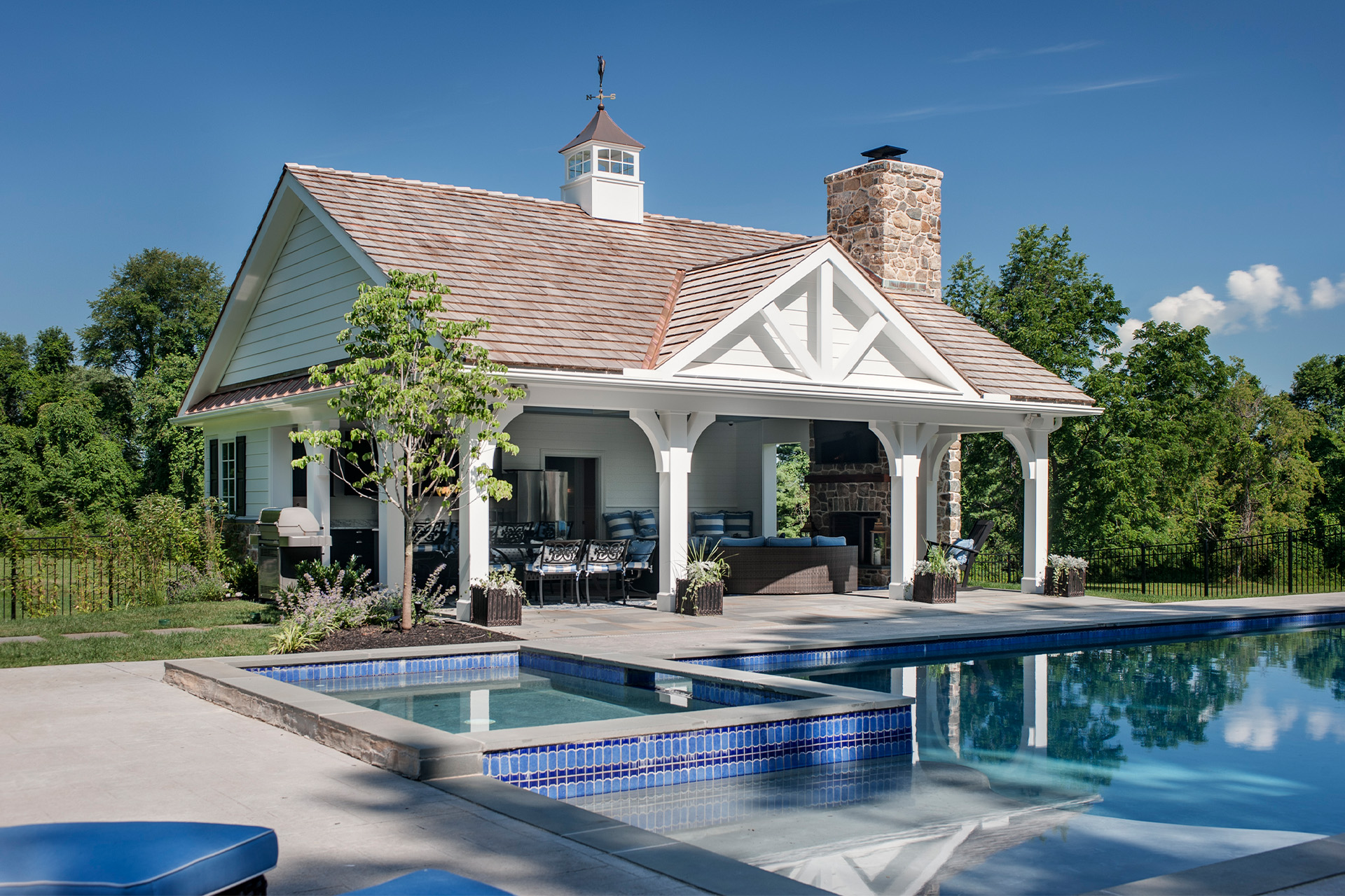 Exterior of a poolhouse showing the pool and hot tub by Hellings Builders