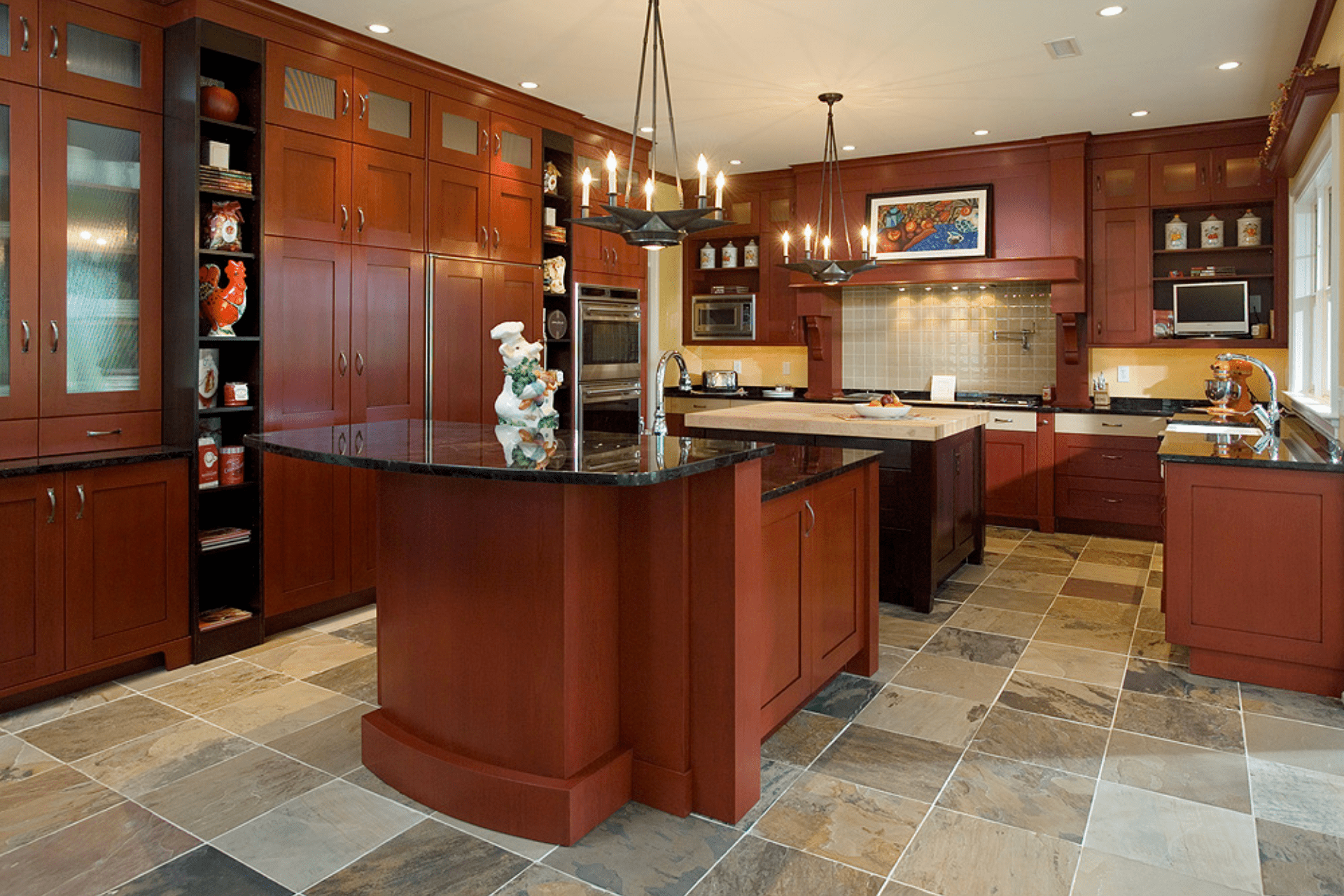 A spacious kitchen features dark wood cabinets and a central island with a black countertop. Stylish overhead lighting illuminates the space, complementing the stone tile flooring. Decorative items enhance the aesthetic.