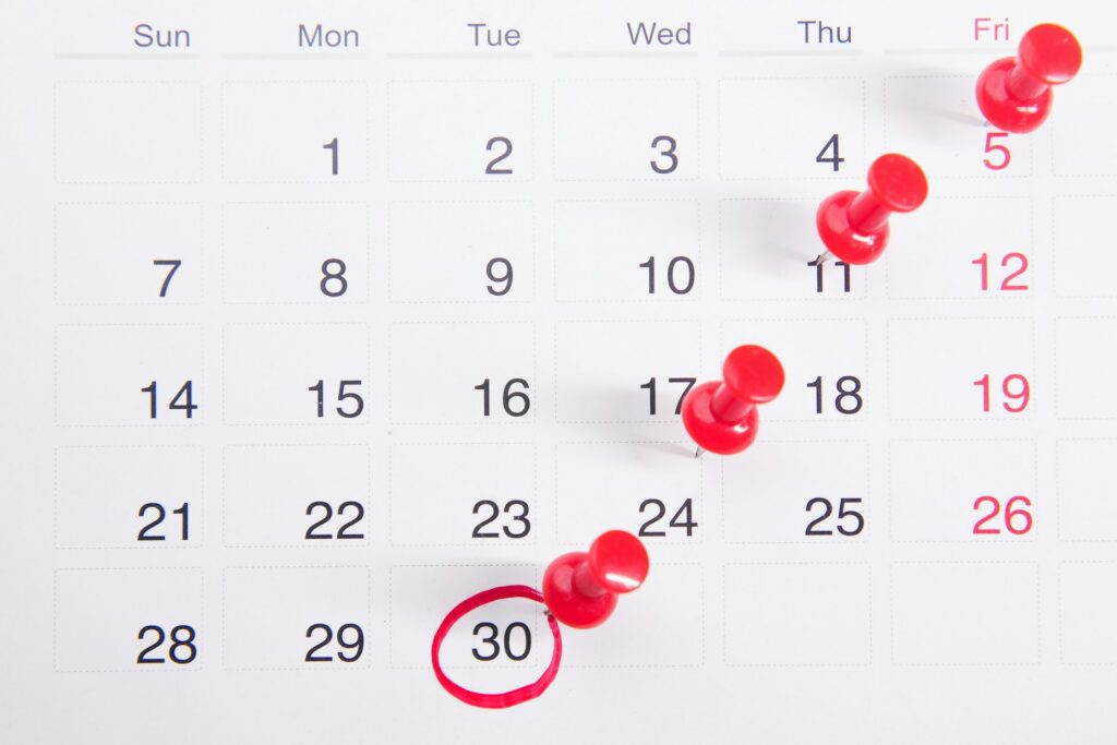 A calendar page with four red pushpins marking Fridays and a red circle around the 30th, which is a Tuesday.